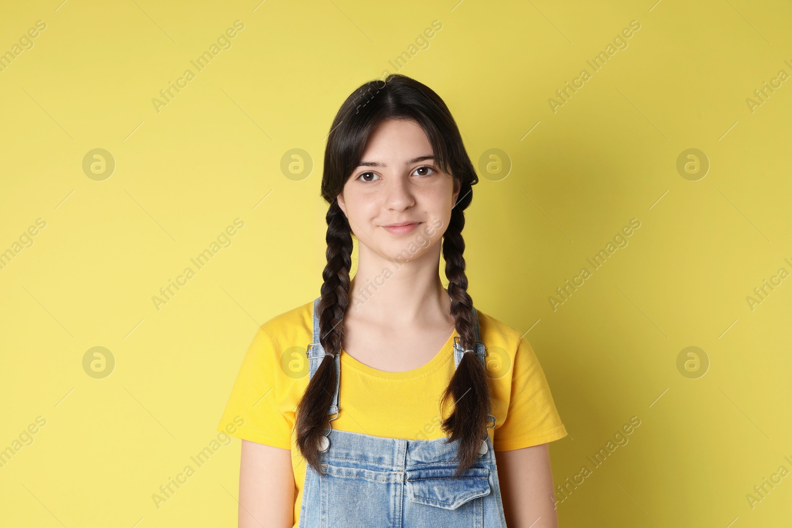 Photo of Portrait of cute teenage girl on yellow background