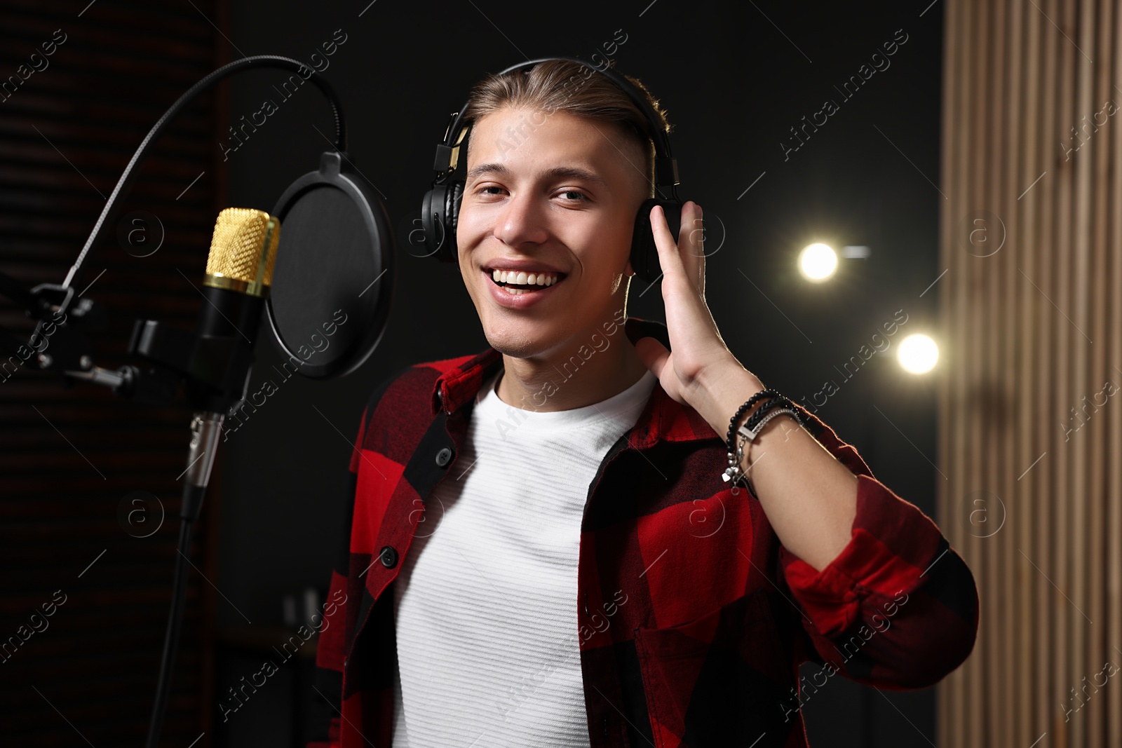 Photo of Singer with headphones recording song in professional studio