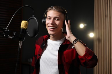 Singer with headphones recording song in professional studio