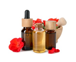 Photo of Bottles of geranium essential oil, mortar and pestle with beautiful flowers isolated on white