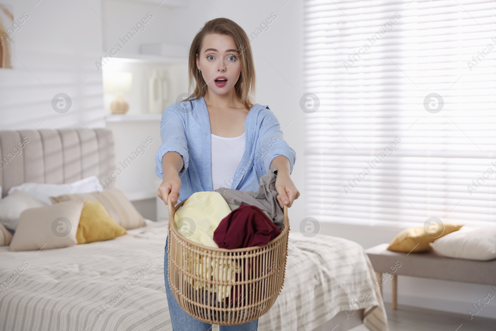 Photo of Emotional housewife with basket full of laundry at home