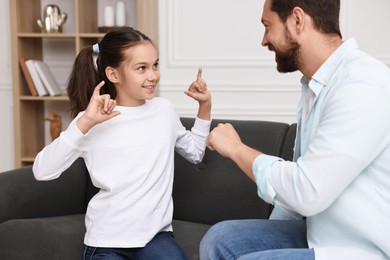 Photo of Man and his daughter using sign language for communication at home