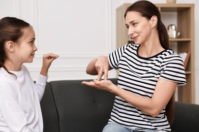 Photo of Woman and her daughter using sign language for communication at home