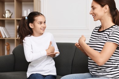 Photo of Woman and her daughter using sign language for communication at home