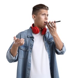 Young man recording voice message via smartphone on white background