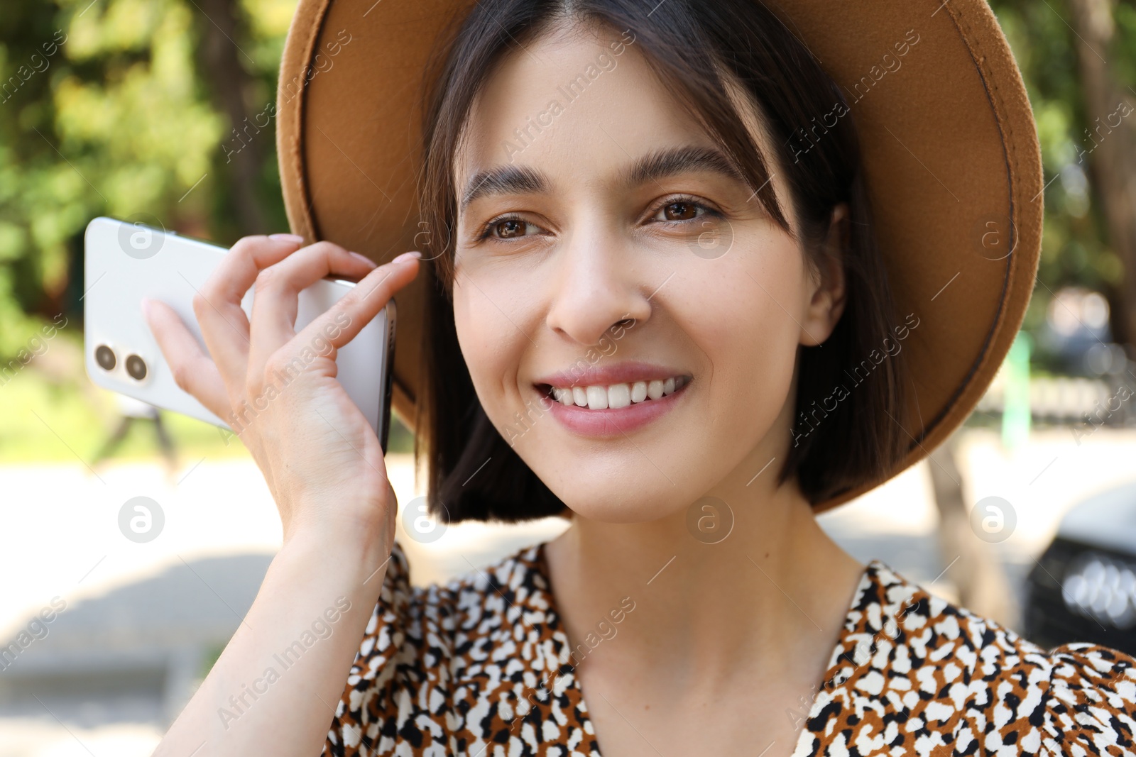 Photo of Beautiful woman with smartphone listening to voice message outdoors