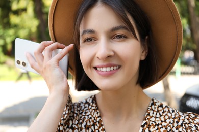 Photo of Beautiful woman with smartphone listening to voice message outdoors