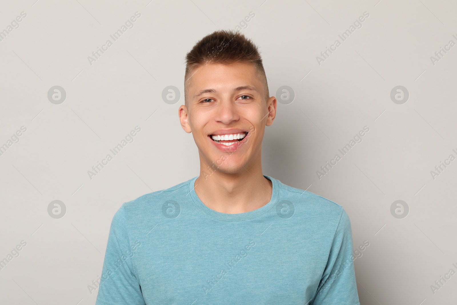 Photo of Happy young man on gray background. Dental veneers