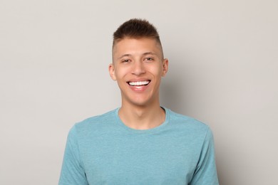 Happy young man on gray background. Dental veneers