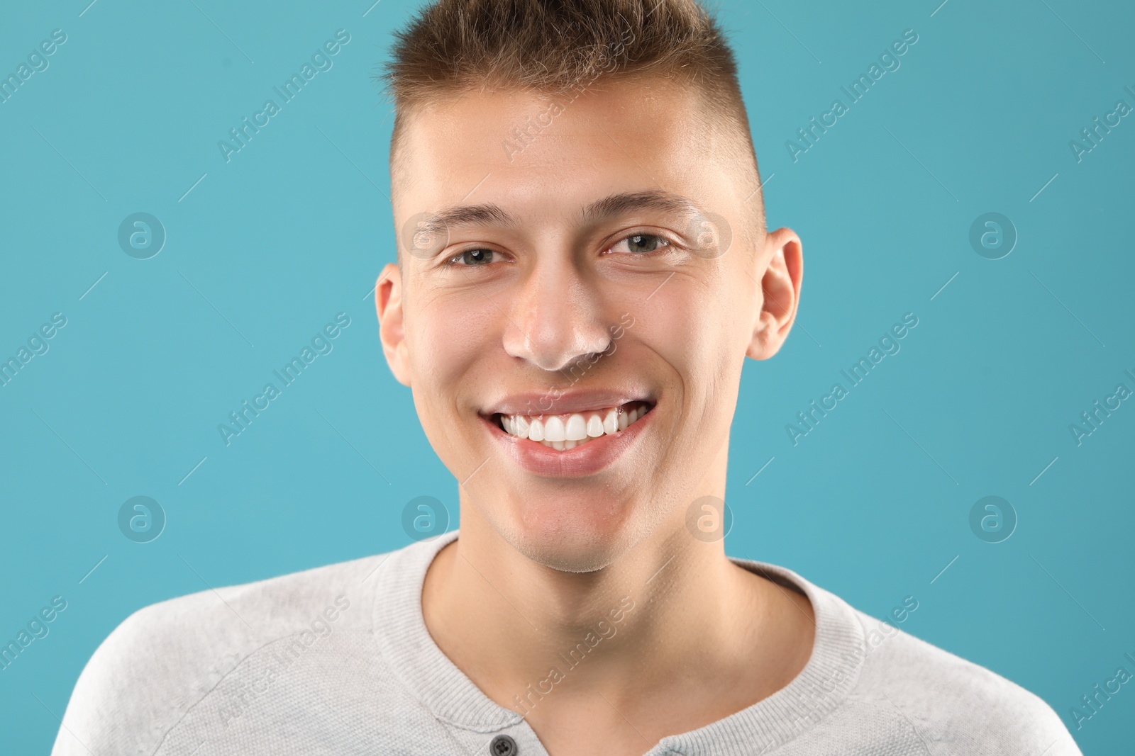 Photo of Happy young man on light blue background. Dental veneers