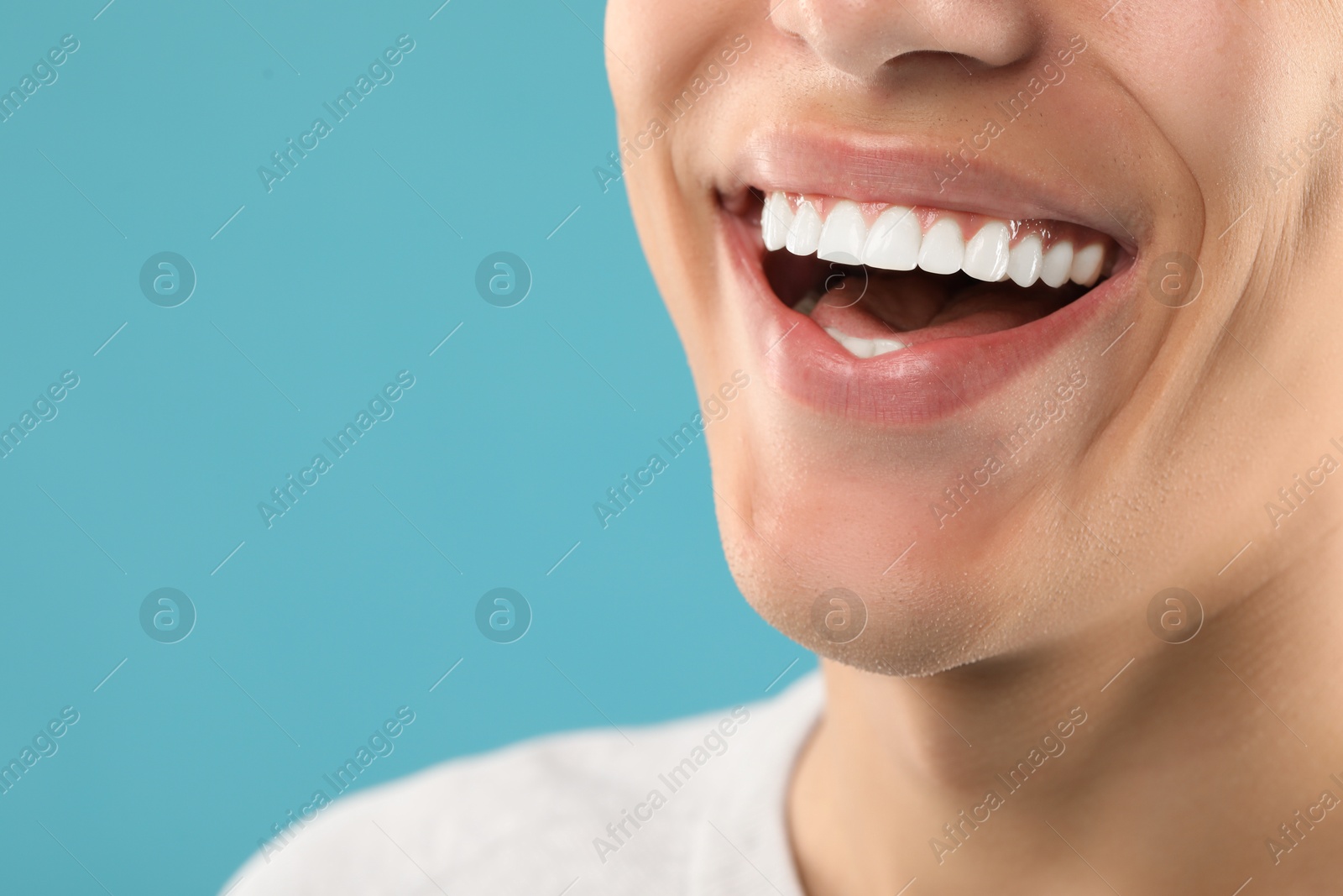 Photo of Happy young man on light blue background, closeup with space for text. Dental veneers