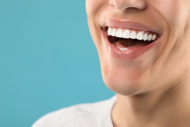 Happy young man on light blue background, closeup with space for text. Dental veneers