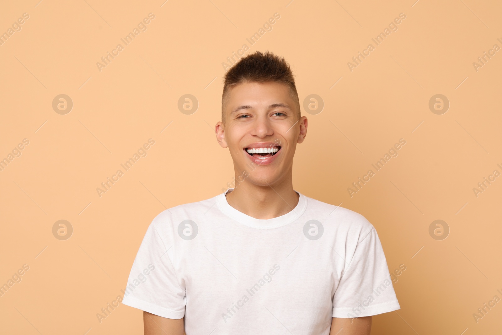 Photo of Happy young man on beige background. Dental veneers