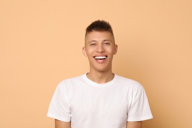 Happy young man on beige background. Dental veneers