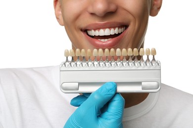 Doctor checking young man's teeth color on white background, closeup. Dental veneers