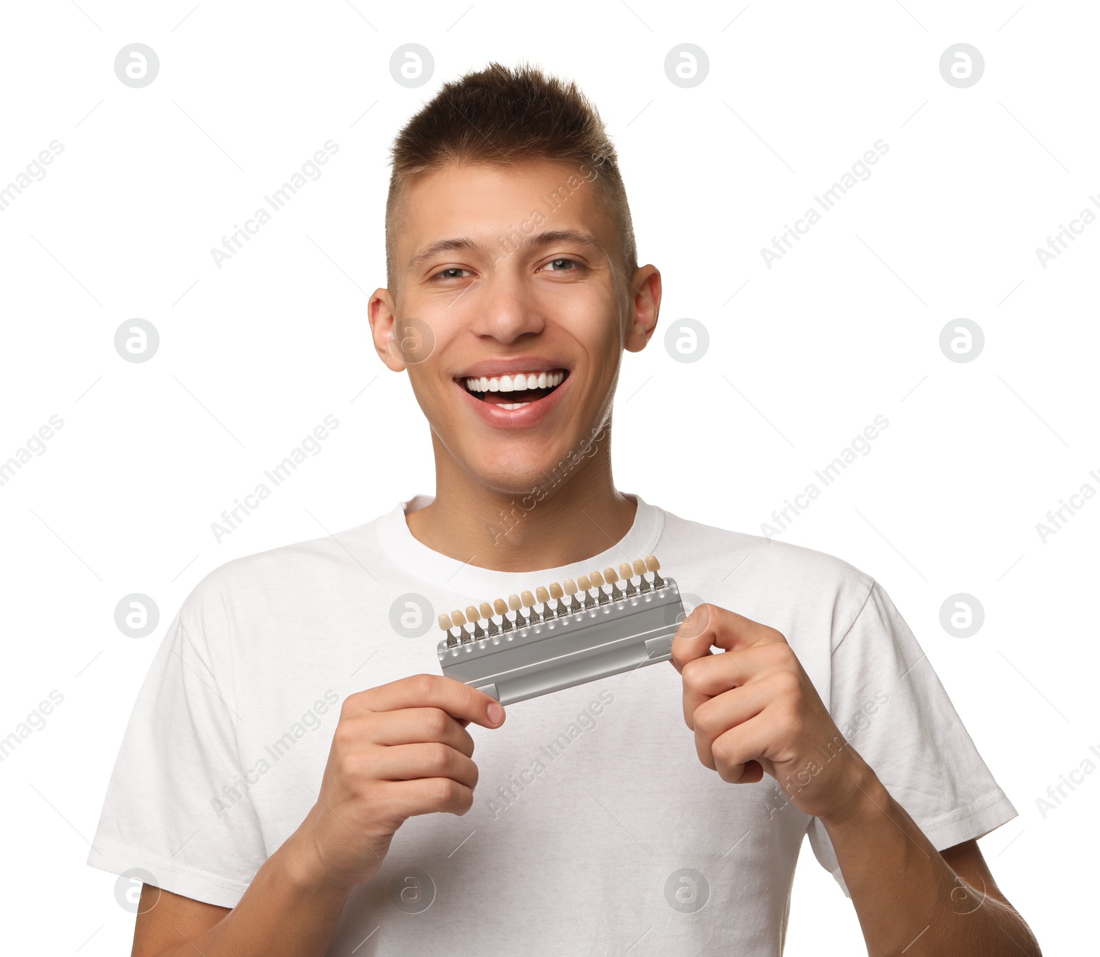 Photo of Happy young man with teeth color samples on white background. Dental veneers