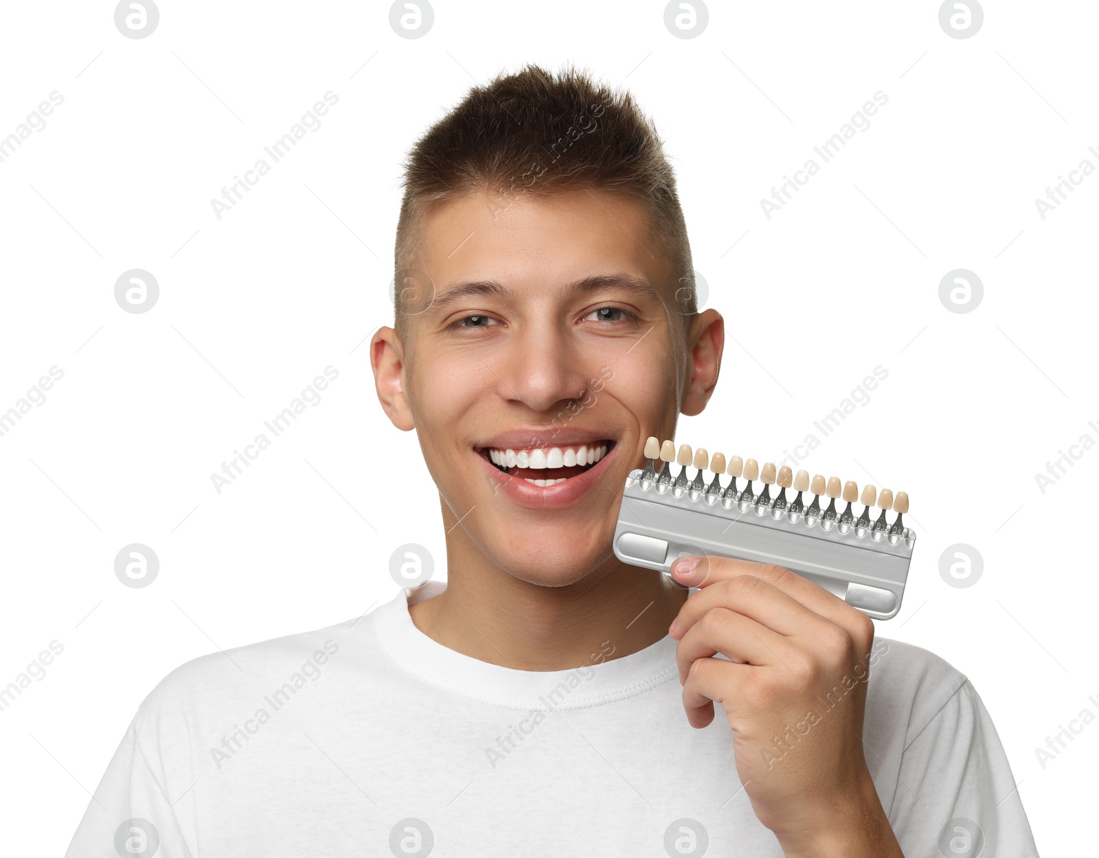 Photo of Happy young man with teeth color samples on white background. Dental veneers