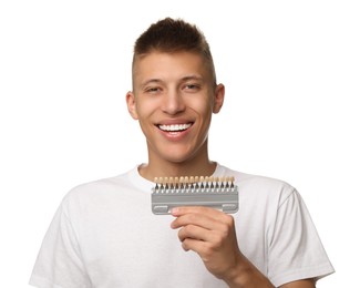 Photo of Happy young man with teeth color samples on white background. Dental veneers