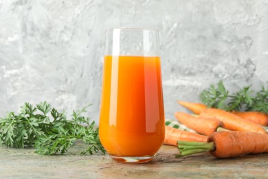 Fresh carrot juice in glass and vegetables on textured table