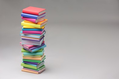 Stack of colorful books on light grey background, space for text