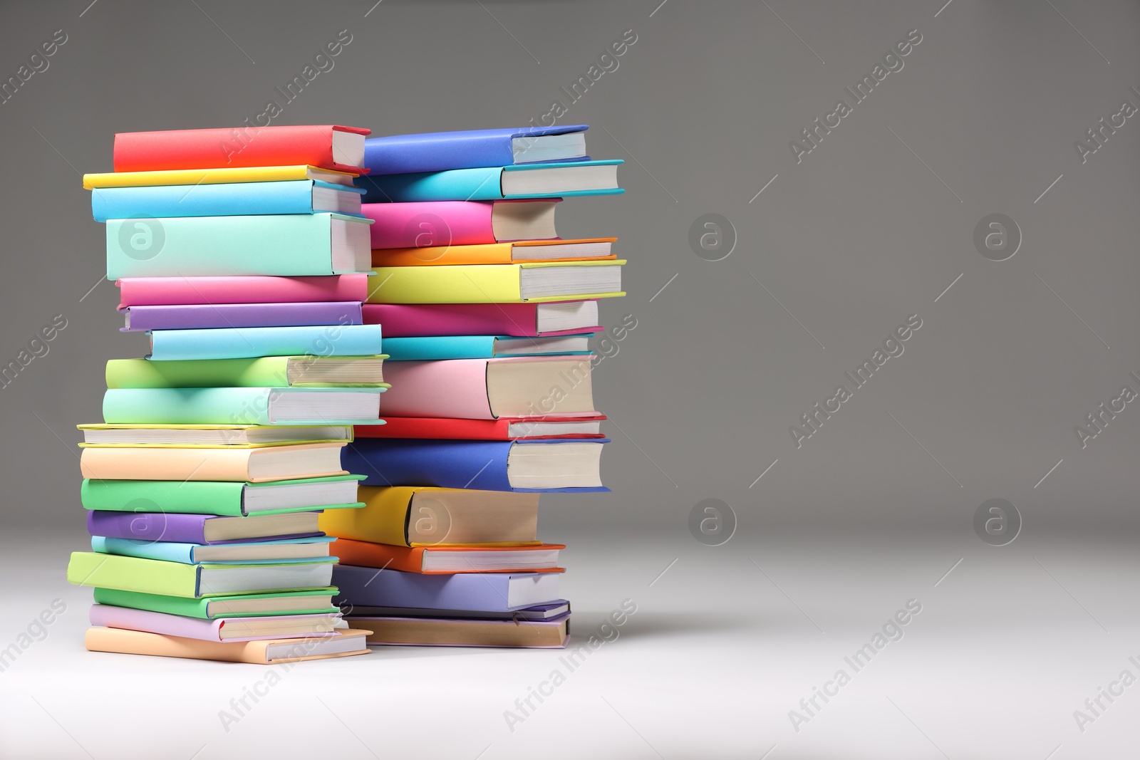 Photo of Stacks of colorful books on light grey background, space for text