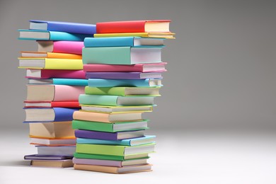 Stacks of colorful books on light grey background, space for text