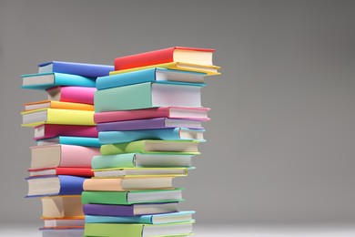 Photo of Stacks of colorful books on light grey background, space for text