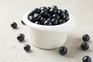 Ripe black currants in bowl on light table, closeup