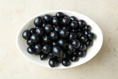 Fresh ripe black currants in bowl on light table, top view