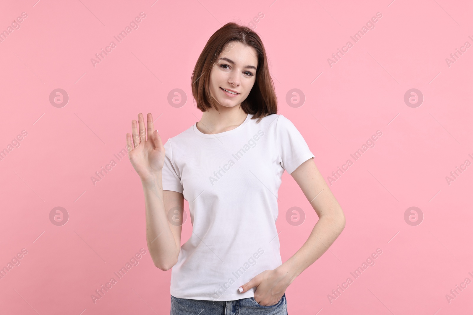 Photo of Happy teenage girl waving on pink background