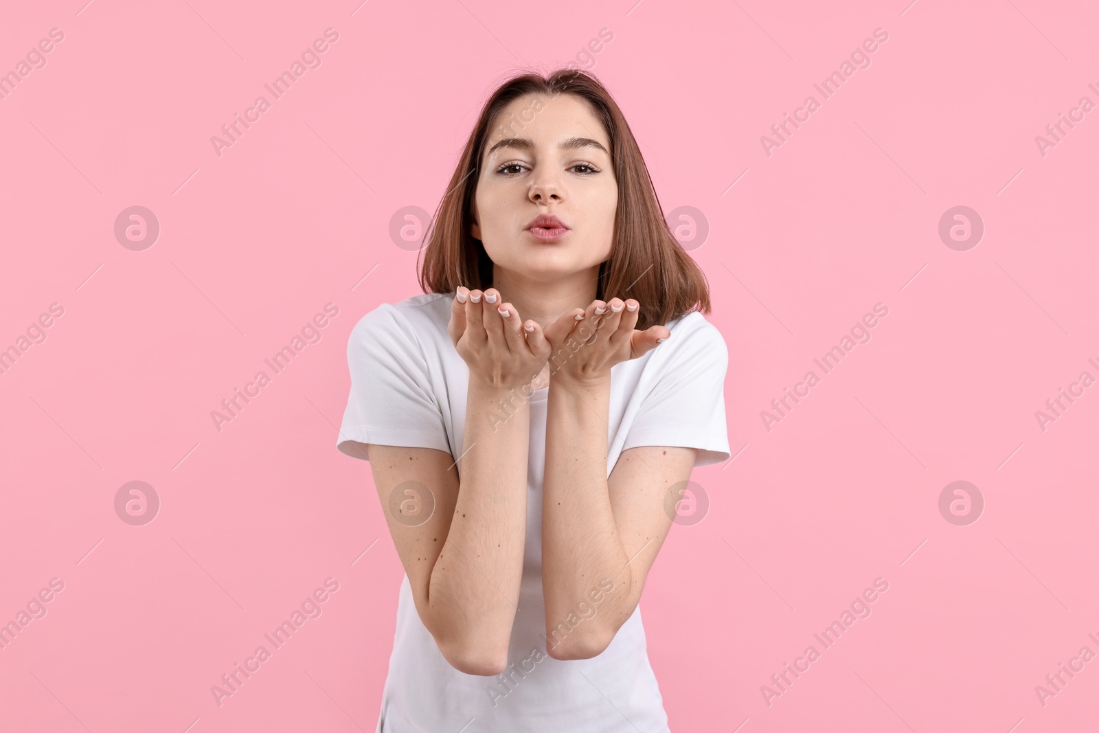 Photo of Beautiful teenage girl blowing kiss on pink background