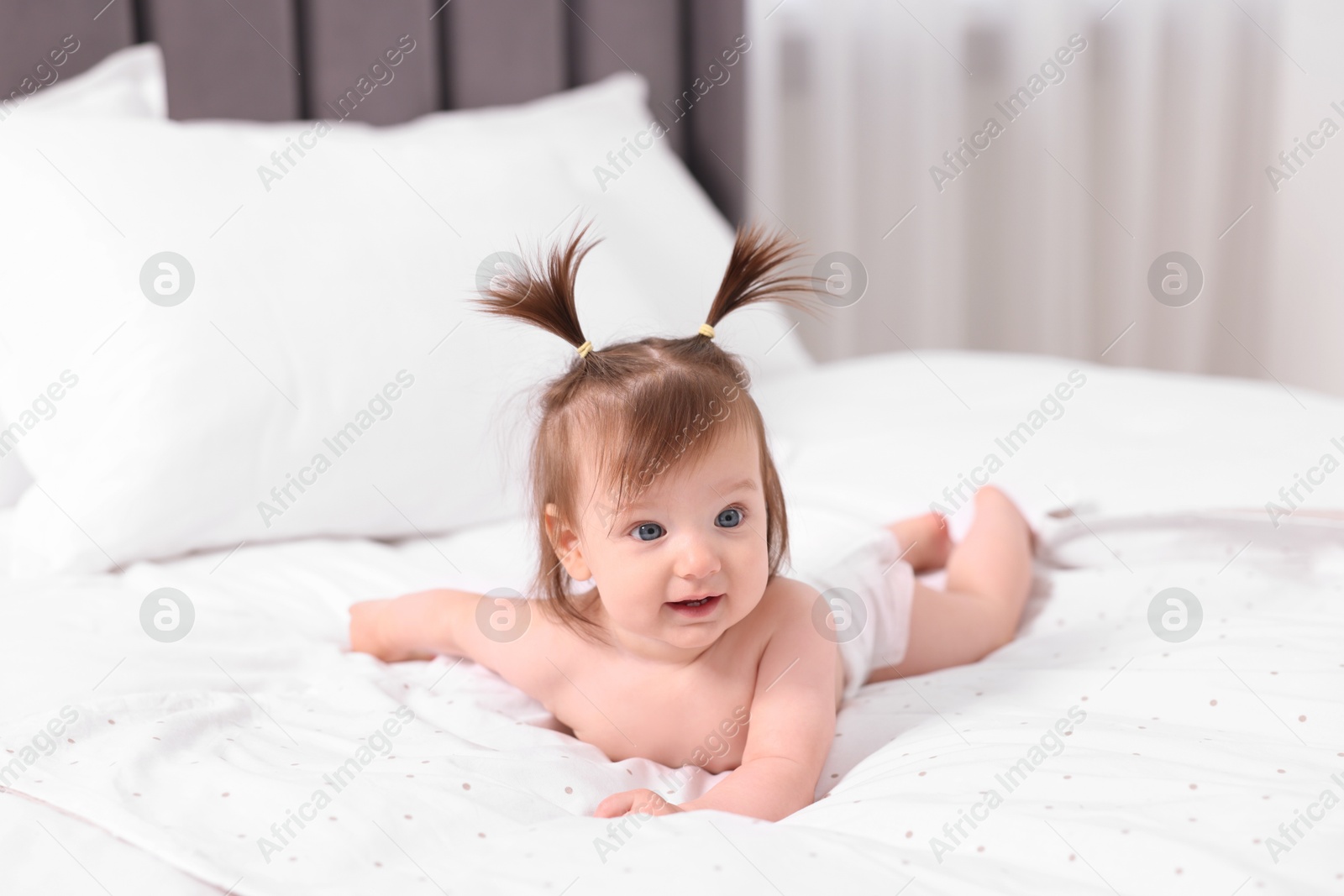 Photo of Cute little girl in diaper lying on bed at home