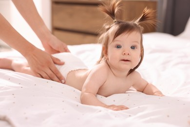 Photo of Mother changing her baby's diaper on bed, closeup