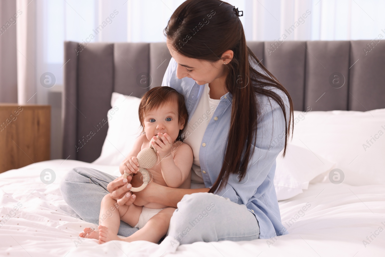 Photo of Mother and her cute baby in diaper on bed