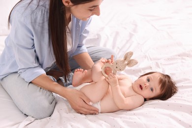 Photo of Mother changing her baby's diaper on bed