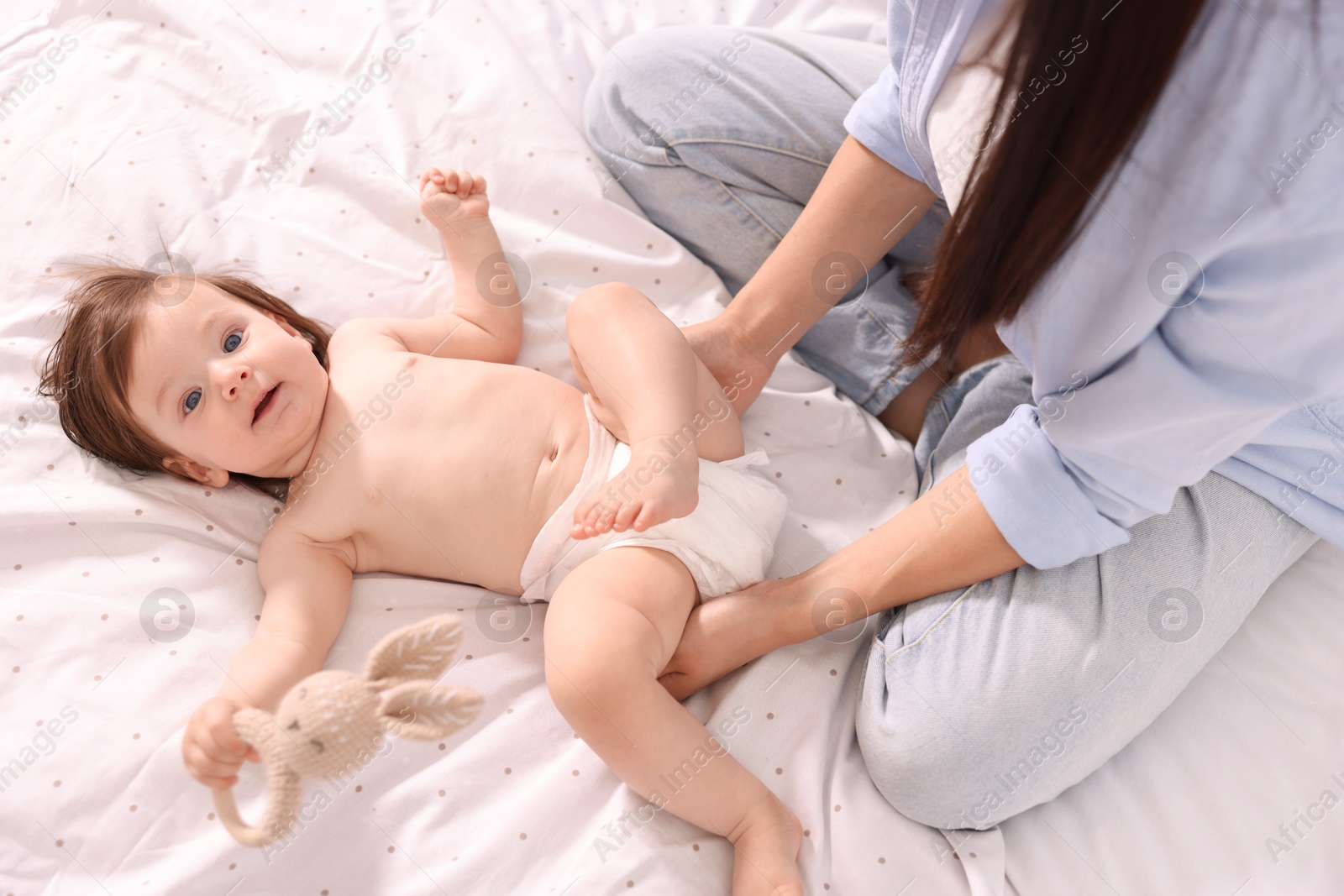 Photo of Mother changing her baby's diaper on bed, above view