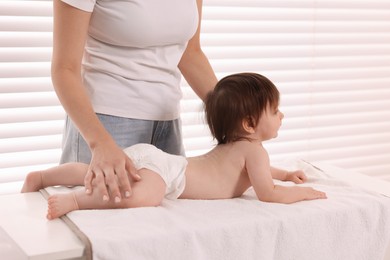 Photo of Mother changing her baby's diaper on table at home, closeup