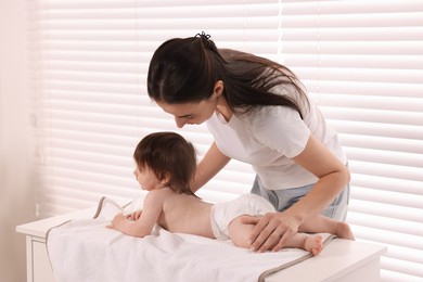 Photo of Mother changing her baby's diaper on table at home