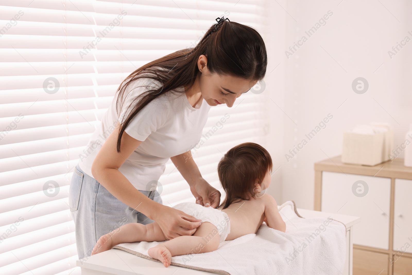 Photo of Mother changing her baby's diaper on table at home