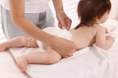 Photo of Mother changing her baby's diaper on table at home, closeup