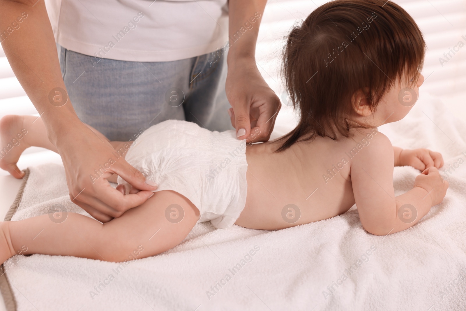 Photo of Mother changing her baby's diaper on table at home, closeup