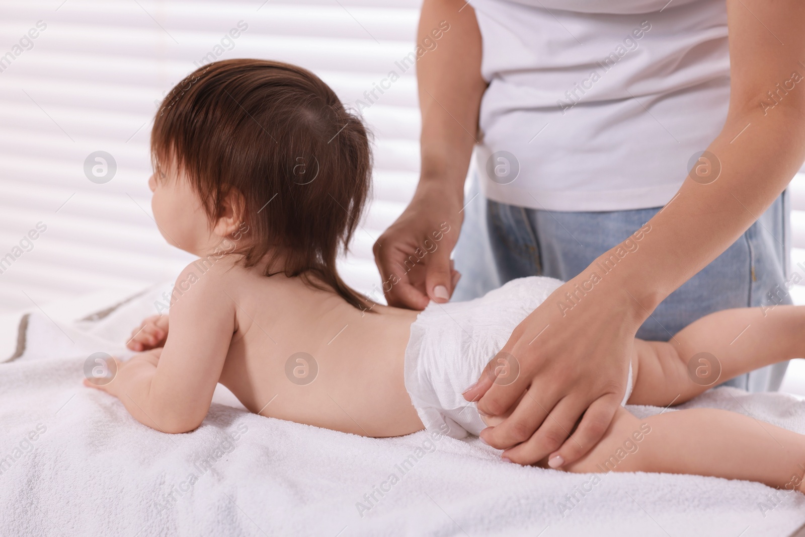 Photo of Mother changing her baby's diaper on table at home, closeup