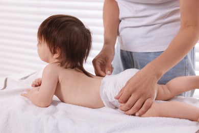 Photo of Mother changing her baby's diaper on table at home, closeup