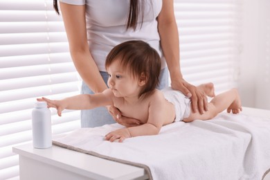 Photo of Mother changing her baby's diaper on table at home, closeup