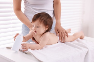 Photo of Mother changing her baby's diaper on table at home, closeup