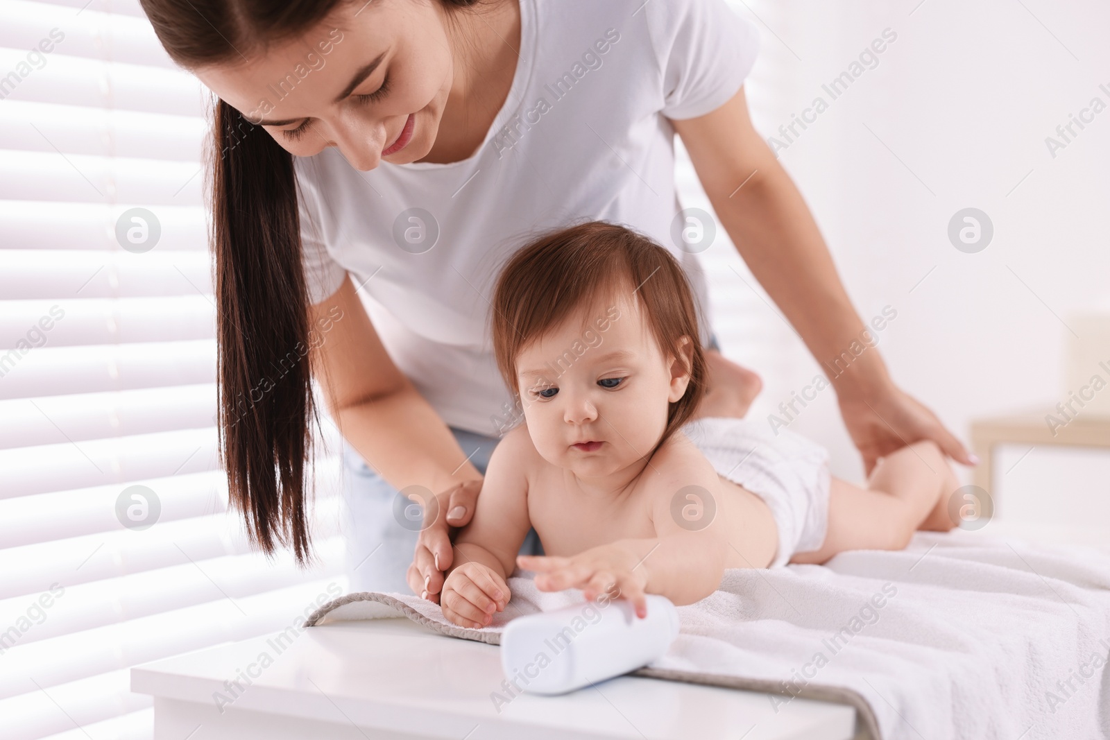 Photo of Mother changing her baby's diaper on table at home