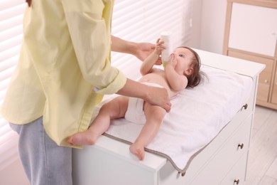 Mother changing her baby's diaper on table at home, closeup