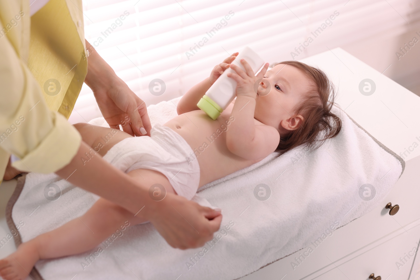 Photo of Mother changing her baby's diaper on table at home, closeup