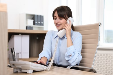 Professional receptionist talking on phone in office