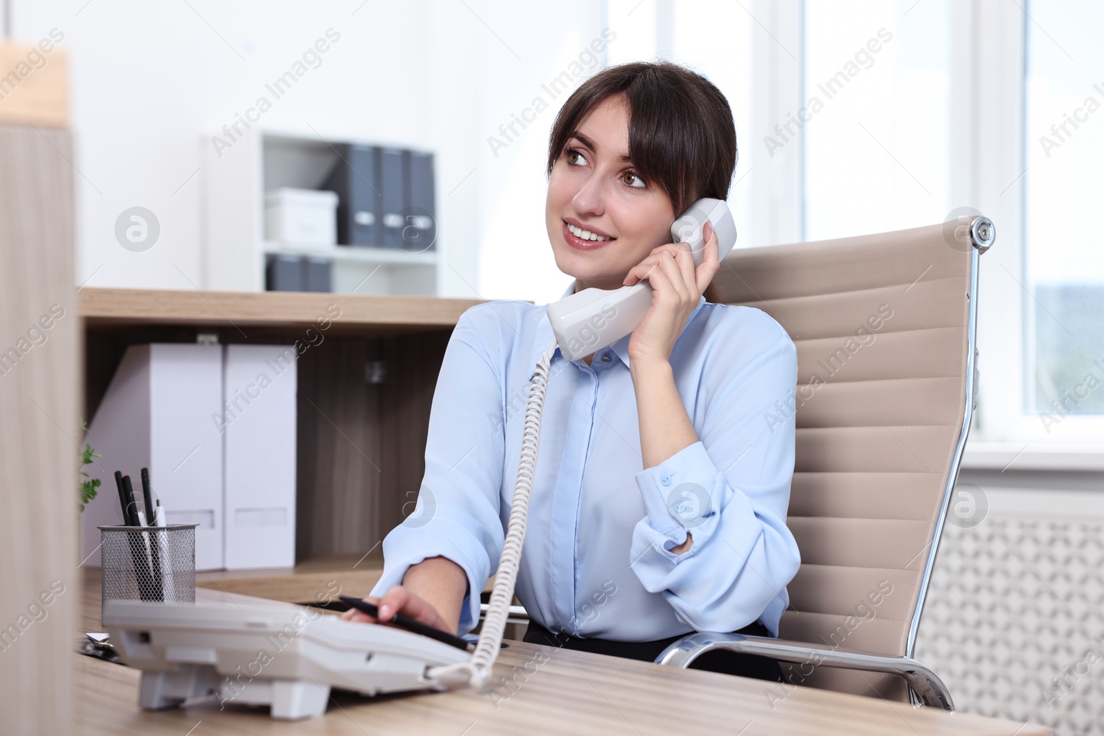 Photo of Professional receptionist talking on phone in office